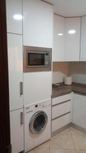 a kitchen with a washing machine and a microwave at Kyara beleza apartamento in Prainha