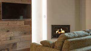 a living room with a fireplace and a couch and a television at Zarabella Delle Alpi in Temù +22 photos