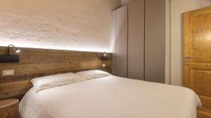 a bedroom with a white bed and a wooden wall at Zarabella Delle Alpi in Temù