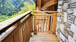 a wooden balcony of a cabin with a stone wall at Zarabella Delle Alpi in Temù