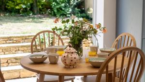 Una mesa de madera con cuencos y un jarrón encima. en Inglenook Cottage, en Charlbury