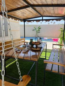 a picnic table with a swinging bench and a pool at Villa Lamys Djerba Houmt Souk à 5 minute du centre ville in Al Hara Al Kabira