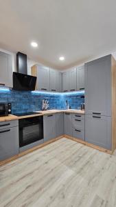 a kitchen with white cabinets and a blue wall at METIS Apartment in Martin +37 photos