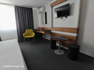 a hotel room with a desk and a yellow chair at Hanul Dintre Vii in Mărăşeşti