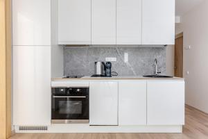 una cucina bianca con mobili bianchi e un lavello di Mill Central a Palanga Altre 11 foto