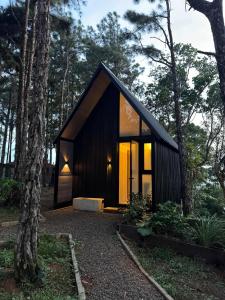 a small black cabin in the woods with trees at Tiny Cabin Cerro Azul in Los Altos de Cerro Azul
