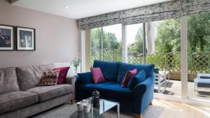 a living room with a blue couch and a large window at Chestnut Lodge in Somerford Keynes +17 photos
