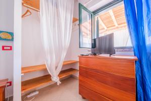 a bedroom with a dresser with a tv and a window at Jerà Suite Vista Mare 19 in Lipari
