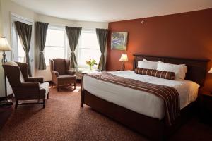 ein Hotelzimmer mit einem großen Bett und zwei Stühlen in der Unterkunft Lanes Riverhouse Inn & Cottages in Montague