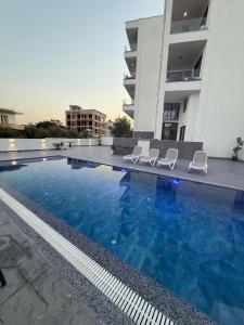 a swimming pool with two chairs and a building at Alpha Blue Apartments in Ksamil