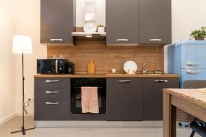 a kitchen with black cabinets and a sink and a stove at La Corte - Monza Apartments in Monza