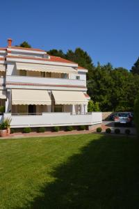 a large building with a green lawn in front of it at Apartment Natasa in Rab