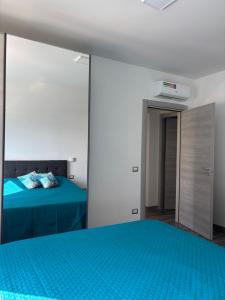 a bedroom with a blue bed and a mirror at Torvajanica Antonella in Torvaianica