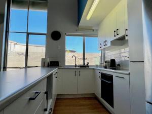 eine Küche mit weißen Schränken und einem großen Fenster in der Unterkunft Tropical Palms - Kalbarri, WA in Kalbarri