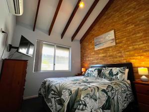 ein Schlafzimmer mit einem Bett und einer Ziegelwand in der Unterkunft Tropical Palms - Kalbarri, WA in Kalbarri