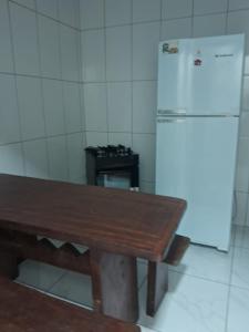a kitchen with a wooden table and a refrigerator at Casa compartilhada em Itaúnas - Centro da Vila in Conceição da Barra