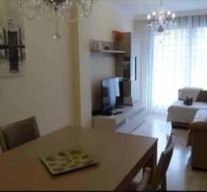 Una sala de estar con una mesa y una sala de estar con un sofá. en LA Escollera II Noja, en Noja