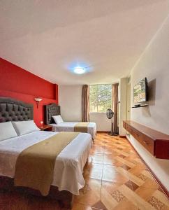 a hotel room with two beds and a red wall at Real Marquez in Trujillo