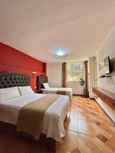 a hotel room with two beds and a red wall at Real Marquez in Trujillo +6 photos