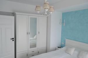 a bedroom with a white bed and a blue wall at Apartament POK in Constanţa