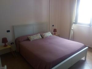 a bedroom with a bed with purple sheets and a window at Casa Vacanze in collina - Marina di Camerota in Lentiscosa
