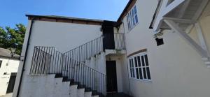 un edificio blanco con una escalera que conduce a una puerta en Plas Bellin Apartments, en Mold
