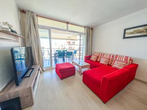 a living room with a red couch and a tv at LITORAL COSTA DORADA - CORAL Only families in Cambrils
