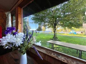Un jarrón de flores en una ventana con un banco. en Balsam Lake - 3-Bedroom Cottage #3, en Kawartha Lakes