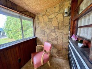 Una silla rosa en una habitación con ventana. en 1-Bedroom Balsam Lake Cottage #9, en Kawartha Lakes