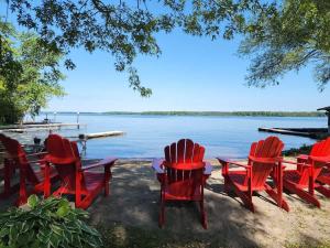 Un grupo de sillas y mesas rojas junto al agua. en Balsam Lake - 2-Bedroom House in Kawartha #15, en Kawartha Lakes 3 fotos más