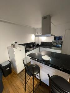 una cocina con encimera negra y sillas. en Duplex Hyper centre cosy, en Auxerre 8 fotos más