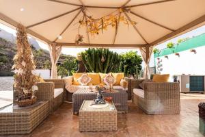 un patio al aire libre con muebles de mimbre y sombrilla en Angels Cabin, en San Bartolomé