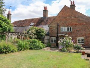 una casa antigua con un jardín delante de ella en 3 Malthouse Cottages, en Alton