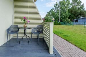 a patio with two chairs and a table with a vase of flowers at Apartamentai Trys pušys in Šventoji