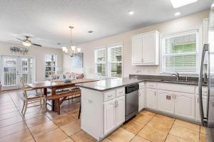 a kitchen with white cabinets and a wooden table at Barefoot Breeze,Steps To The Beach ,Pool ,Sleeps 13, Seacrest in Seacrest