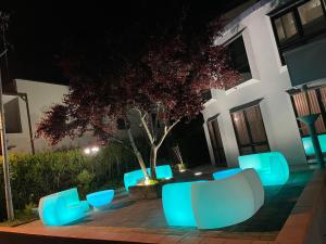 a patio with blue chairs and a tree at night at Hotel Sirena & Cucina in Cesenatico