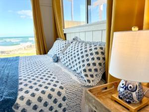 ein Schlafzimmer mit einem Bett und einem Tisch mit einer Lampe in der Unterkunft Oceanfront Stay w/ AC, BBQ, Washer/Dryer & Kitchen in Ewa Beach