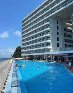 a hotel swimming pool next to a large building at Bamboo Beach Tsikhisdziri, Solmare Loft in Itʼkhvisi