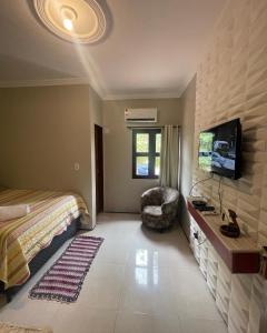 una camera con letto, TV e sedia di Pousada Delicias da vila a Jericoacoara