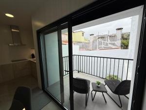 einen Balkon mit Stühlen und einem Tisch und eine Küche in der Unterkunft Casa do Lago das Freiras in Ribeira Grande