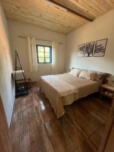 a bedroom with a bed and a wooden floor at Rancho Vô de Ochinho in Sapucaí-Mirim
