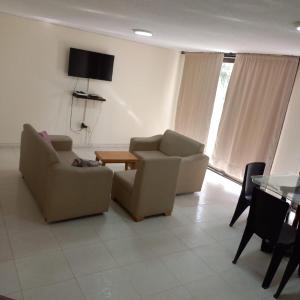 a living room with two chairs and a table at Apartamento frente al mar y la playa Rodadero in Rodadero
