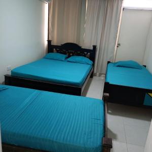 three beds in a room with blue sheets at Puesta del sol in Rodadero