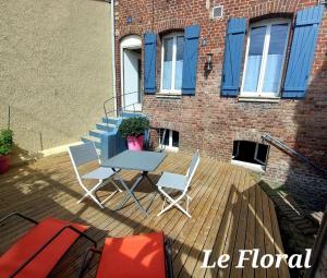 a patio with a table and chairs on a deck at Les Belles Terrasses Dieppe ,3 appartements , LE VEGETAL de 1 à 8 personnes , LE TROPICAL de 1 à 6 personnes , LE FLORAL avec TERRASSE de 1 à 3 personnes , quartier calme au stationnement gratuit à coté de l'avenue verte in Dieppe