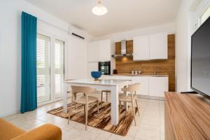 a kitchen and dining room with a white table and chairs at Villademar lunarossa in Marzamemi