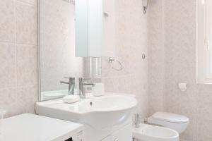a white bathroom with a sink and a toilet at Burlo Garofalo Elegant Apartment Near Hospital in Trieste +15 photos