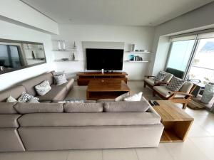 a living room with a couch and a flat screen tv at Departamento con Vista a Mar Icon Vallarta Piso 15 in Cedro