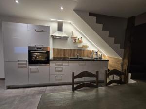 a kitchen with white cabinets and a stove top oven at Chambre 2 P à Saint Hubert in Saint-Hubert
