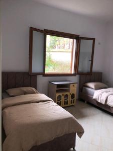 a bedroom with two beds and a window and a mirror at Vila Mehalla in Arape-Rashbulli