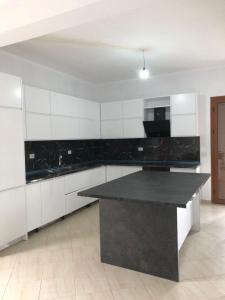 a kitchen with white cabinets and a black counter top at Vila Mehalla in Arape-Rashbulli